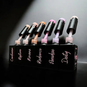 Row of black nail polish bottles with dripping brushes displaying different shades of pink and nude colors.